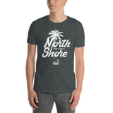 Young male adult wearing a Alter Ego Hawaii T-shirt that has a Hawaii themed graphic logo on the front.