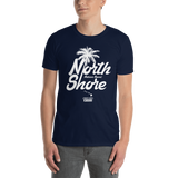 Young male adult wearing a Alter Ego Hawaii T-shirt that has a Hawaii themed graphic logo on the front.