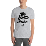 Young male adult wearing a Alter Ego Hawaii T-shirt that has a Hawaii themed graphic logo on the front.